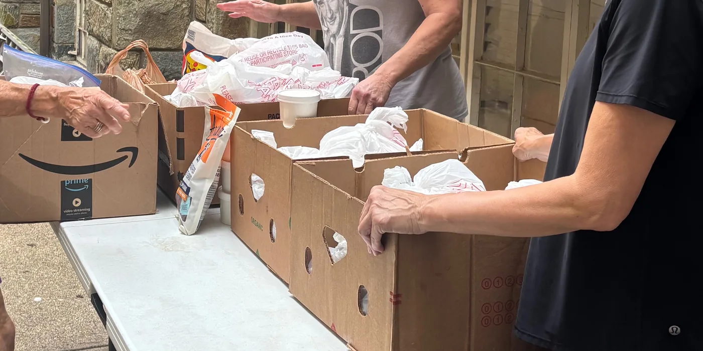 Volunteers packing boxes of surplus bread at a folding table